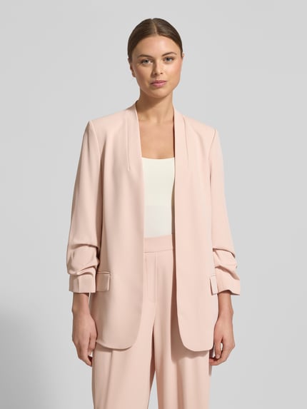Modelka nosi Blazer mit Pattentaschen von Jake*s Collection w kolorze jasnoróżowym, mieszanka materiałów z dodatkiem streczu, luźny krój, stójka, kieszenie z patką, rękaw o dł. 3/4, długość tyłu w rozmiarze 36: 69 cm, szerokość w rozmiarze 36: 44 cm, długość rękawów w rozmiarze 36: 52 cm; zdjęcie z przodu, ujęcie całej sylwetki.