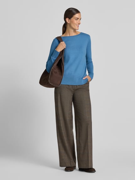 Frauenmodel trägt Regular Fit Strickpullover aus Viskose-Mix mit U-Boot-Ausschnitt von Christian Berg Woman, blaue Farbe, gerippte Abschlüsse, langärmlig, überschnittene Schultern, kombiniert mit karierter Hose, Struktur glatt, Ganzkörperansicht von vorne.