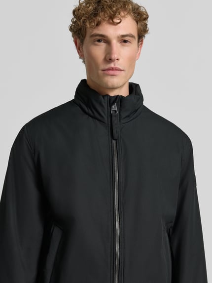 Männermodel trägt schwarze Regular Fit Steppjacke mit Stehkragen Modell 'LIGHT' von Strellson, Herren Steppjacke, Nahaufnahme Oberkörper.