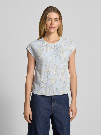 Frauenmodel trägt Regular Fit Bluse aus reiner Viskose von s.Oliver BLACK LABEL, hellblaues Allover-Muster, ohne Ärmel, Ganzkörperansicht von vorne.
