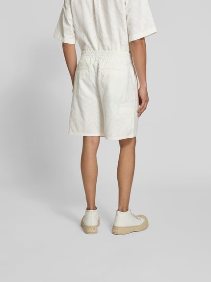 Männermodel trägt Shorts mit Strukturmuster von Kenzo in Cremeweiß, reine Baumwolle, Straight Fit, Rückansicht Ganzkörperansicht.