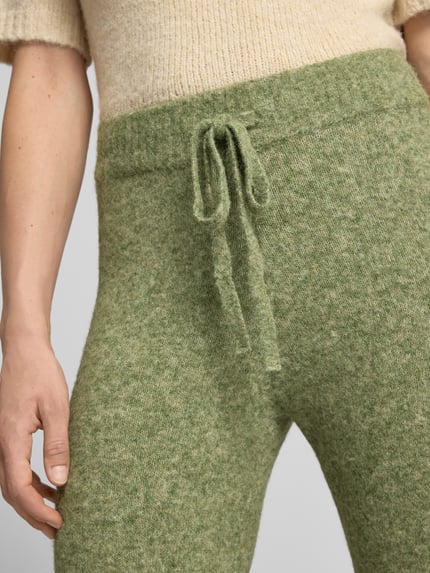 Frauenmodel trägt Hose mit Strickoptik von VERO MODA in meliertem Grün, elastischer Bund mit Tunnelzug, Nahaufnahme Oberkörper, Damen Weite Hose, Strick, Schlupfverschluss.