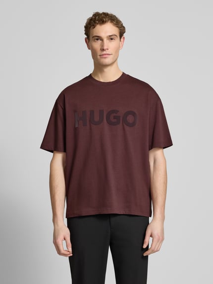 Męski model nosi Oversized T-Shirt aus reiner Baumwolle Modell 'DINKEE' von HUGO, kolor jednolity, label print, okrągły dekolt, krótki rękaw, czysta bawełna, Ganzkörperansicht von vorne.