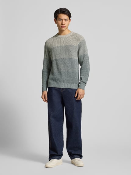 Männermodel trägt Relaxed Fit Strickpullover aus reiner Baumwolle Modell 'BIRK' von Only & Sons im melierten Ombré-Look, Ganzkörperansicht von vorne.