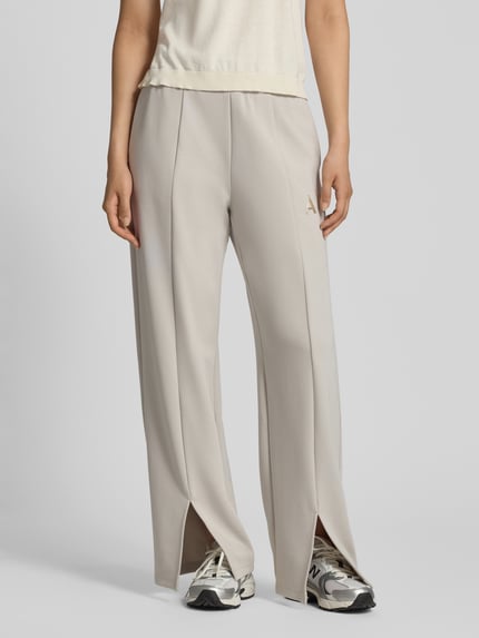 Frauenmodel trägt Straight Fit Sweatpants aus elastischem Viskose-Mix von Armani Exchange in Beige mit Label-Detail und Bein-Schlitzen, Nahaufnahme Unterkörper. Damen Sweatpants, elastischer Bund, Innenbeinlänge Größe S 77 cm.