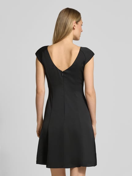 Modelka nosi Knielanges Kleid mit Raffungen od ARMANI EXCHANGE, taliowany krój, długość do kolan, okrągły dekolt, marszczenia, długość tyłu w rozmiarze 36: 93 cm, szerokość klatki piersiowej w rozmiarze 36: 42 cm, czarny kolor, gładka faktura, widok całej sylwetki z tyłu.