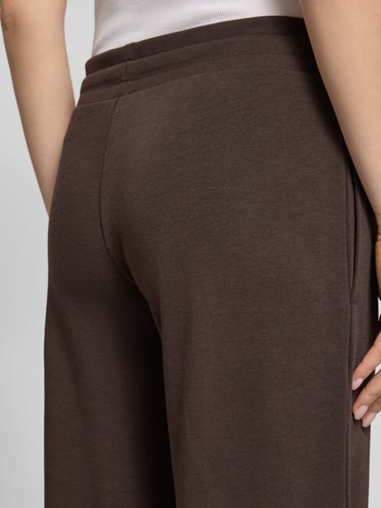Frauenmodel trägt Straight Fit Sweatpants mit Tunnelzug von REVIEW aus braunem Baumwoll-Mix, elastischer Bund, Detailaufnahme Rückansicht.