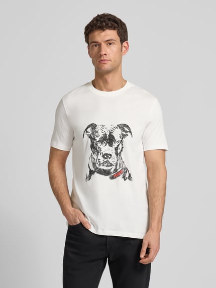 Männermodel trägt Regular Fit T-Shirt aus reiner Baumwolle Modell 'DUBROX' von HUGO, weiß, Rundhals, Motiv-Print, Ganzkörperansicht von vorne.