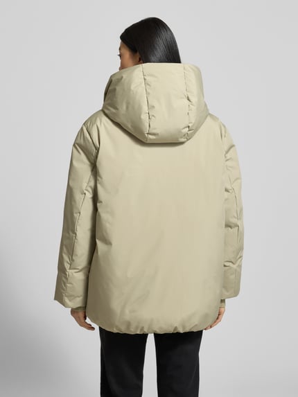 Frauenmodel trägt Regular Fit Outdoor-Jacke mit Stehkragen Modell 'Helah' von Opus in Beige mit Kapuze, elastischen Ärmelabschlüssen, Rückenlänge bei Größe 36: 74 cm, Schulterbreite 53 cm, Brustweite 54 cm, Ärmellänge 63 cm, matte Oberfläche, Ganzkörperansicht Rückansicht.