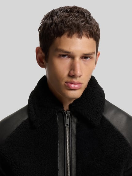 Männermodel trägt Lederjacke Modell 'Laran' mit Schnalle von HUGO in Schwarz, Struktur-Lederoptik, Nahaufnahme Oberkörper.