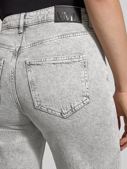 Frauenmodel trägt Wide Leg Jeans aus bawełnianego miksu model 'TESSA' od Vero Moda, efekt: jednolity kolor, label patch, denim, 5 kieszeni, naszywka z logo, mieszanka bawełny, detailaufnahme tylnej kieszeni.