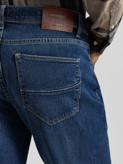 Männermodel trägt Straight Fit Jeans mit 5-Pocket-Design Modell 'Cadiz' van Brax, blauwe denim, detailopname achterkant, katoen-lyocell-mix met modal.