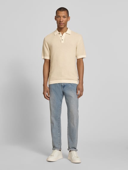 Männermodel trägt Regular Fit Poloshirt in Strick-Optik Modell 'Kingsley' von Jack & Jones Premium, beige, reine Baumwolle, Ganzkörperansicht von vorne.