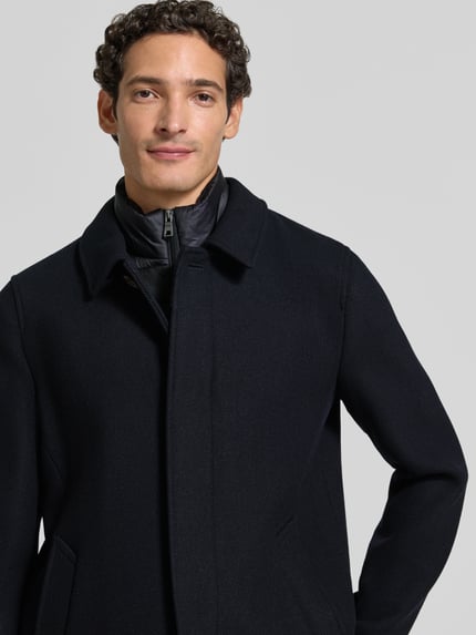 Männermodel trägt Jacke im 2-in-1-Look von Geox in Schwarz, Umlegekragen, verdeckter Reißverschluss, Nahaufnahme Oberkörper.