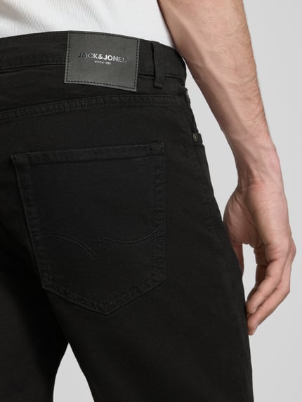 Männermodel trägt schwarze Jeansshorts mit Umschlag und Eingrifftaschen Modell 'RICK ALLEN' von Jack & Jones, Detailaufnahme Rückansicht, Baumwoll-Elasthan-Mix, Regular Fit, dezente Struktur.