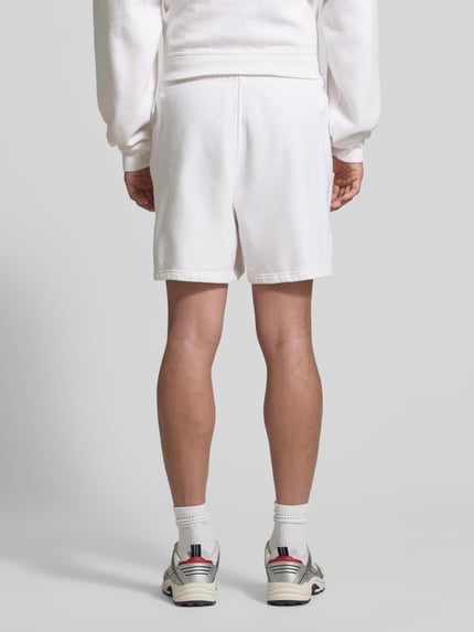 Männermodel trägt Shorts mit Logo Modell 'PLIZZY' von American Vintage aus Reine Baumwolle im Relaxed-Fit, weiß, Ganzkörperansicht Rückansicht.
