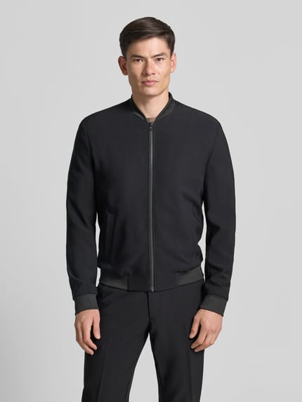 Męski model nosi Blouson mit seitlichen Eingrifftaschen von MCNEAL, czarny, materiał z dodatkiem stretchu, krój regular fit, całkowity przód,