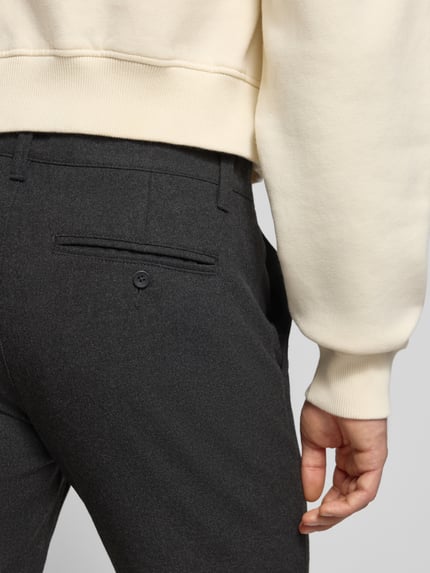 Männermodel trägt Slim Fit Chino mit Viskose-Anteil Modell 'MARK' von Only & Sons, Melange-Optik, feine Webstruktur, Detailaufnahme Rückansicht.