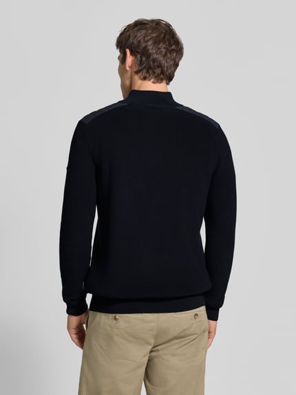 Männermodel trägt gebreide pullover met schoudervulling van puur katoen in recht model, schipperskraag, ribboorden, ruglengte maat M 68 cm, mouwlengte maat M 70 cm, Strickpullover mit gepolsterten Schultern van bugatti, Ganzkörperansicht Rückansicht.