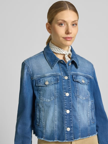 Frauenmodel trägt Cropped Jeansjacke mit Fransen von Marc Cain aus Baumwoll-Elasthan-Mix, Knopfleiste, Brusttasche, Nahaufnahme Oberkörper