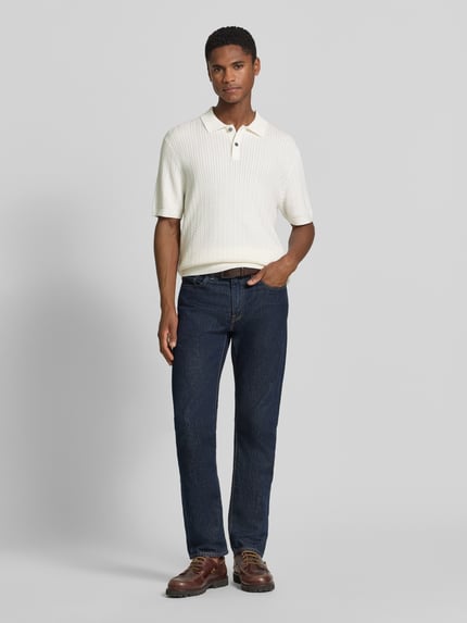 Męski model nosi Regular Fit Poloshirt mit Strukturmuster von Christian Berg Men, kołnierzyk polo, listwa guzikowa, długość tyłu 72 cm, długość rękawów 25 cm, widok całej sylwetki z przodu.