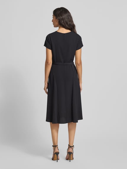Kobiece modelka nosi Knielanges Kleid mit Taillengürtel od Lauren Ralph Lauren, taliowany krój, długość do kolan, wycięcie w kształcie łezki, pasek w talii, wszyty zamek błyskawiczny, długość tyłu 99 cm, szerokość klatki piersiowej 34 cm, długość rękawów 14 cm, czarny kolor, widok całej sylwetki z tyłu.