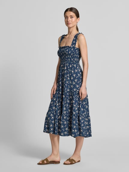 Vrouwenmodel draagt Midikleid mit Rüschen und Karree-Ausschnitt von Apricot, donkerblauw met bloemdessin, zuiver viscose, getailleerd model, vierkante hals met ruches, smokdetails, volantzoom, ruglengte maat S 98 cm, borstwijdte 32 cm, volledig zicht van voren.