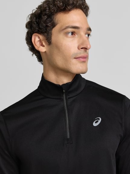 Männermodel trägt Funktionsshirt mit Logo und Reißverschluss von ASICS, schwarzer Material-Mix mit Stretch, Nahaufnahme Oberkörper