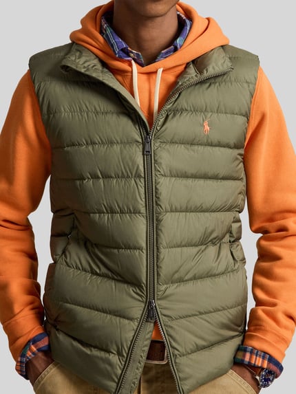 Männermodel trägt Regular Fit Weste mit Logo-Stitching von Polo Ralph Lauren in Olivgrün auf orangefarbenem Hoodie, Nahaufnahme Oberkörper. Herren Weste von Polo Ralph Lauren