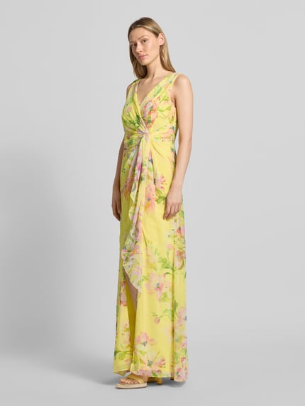 Vrouwenmodel draagt Maxikleid in Wickel-Optik mit V-Ausschnitt van Adrianna Papell, gele vloeiende stof, all-over look, getailleerd model, ruglengte maat 36 148 cm, borstwijdte maat 36 41 cm, all-over bloemenprint, Ganzkörperansicht van voren.