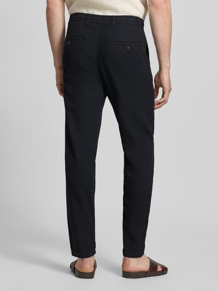 Männermodel trägt Regular Fit Hose aus Baumwoll-Leinen-Mix Modell 'BRODY' von SELECTED HOMME in dunklem Unifarben, Ganzkörperansicht Rückansicht.