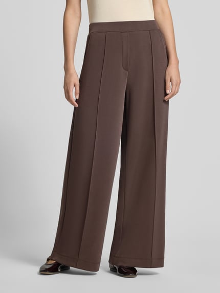 Kobiece modelka nosi spodnie 'Wide Fit Hose mit Viskose-Anteil' od COMMA, brąz, obszerne nogawki, elastyczna mieszanka materiałów z dodatkiem wiskozy, ozdobna kokarda na pasie, szerokość w rozmiarze 36: 37 cm, długość wewnętrzna nogawki w rozmiarze 36: 77 cm, widok na całe ciało z przodu.