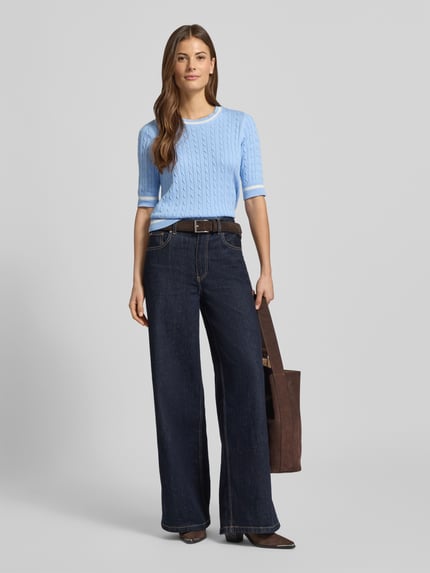Frauenmodel trägt Strickpullover mit gerippten Abschlüssen von Christian Berg Woman aus Baumwoll-Mix, Regular-Fit, Rundhalsausschnitt, 1/2-Ärmel, hellblau mit dezentem Strukturmuster, kombiniert mit dunkler Jeans, Ganzkörperansicht von vorne.