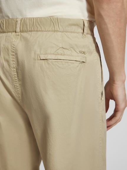 Männermodel trägt Hose mit französischen steekzakken Modell 'Ethan' van Wood Wood van puur katoen in beige, detailaufnahme achterkant.