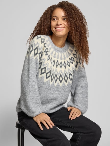Frauenmodel trägt Pullover mit Jacquardpasse von ONLY in grauer Strickoptik, geometrisches Rauten-Muster, Nahaufnahme Oberkörper.