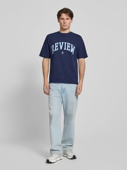 Männermodel trägt T-Shirt mit Label-Print und Rundhalsausschnitt von REVIEW, Herren T-Shirt, Reine Baumwolle, Regular-Fit, Rückenlänge 69 cm, Ganzkörperansicht von vorne.