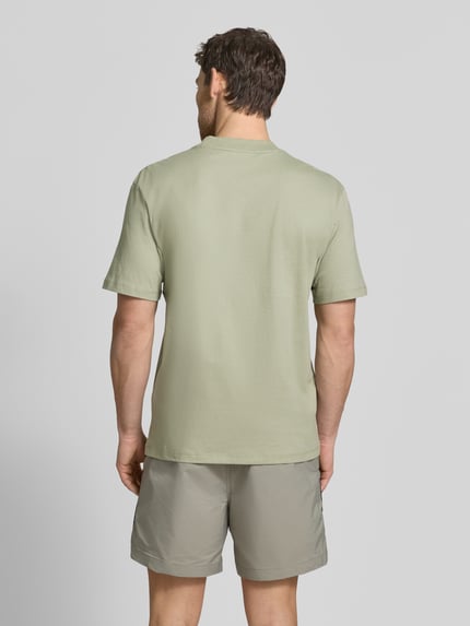 Mężczyzna model nosi Regular Fit T-Shirt aus reiner Baumwolle Modell 'DAPOLINO' od HUGO w jednolitym jasnozielonym kolorze, tkanina jersey, widok całej sylwetki od tyłu.
