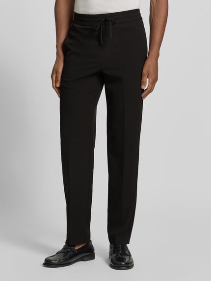 Männermodel trägt Relaxed Fit Sweatpants mit Viskose-Anteil von Lindbergh in Schwarz, Elastischer-Material-Mix, Bügelfalten, Nahaufnahme Oberkörper. Bundweite 41 cm, Innenbeinlänge 79 cm, Größe M, elastischer Bund mit Tunnelzug.