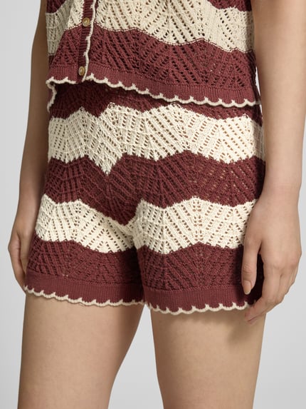 Vrouwenmodel draagt Regular Fit Shorts uit pure katoen model 'GOLDEN COVE' van Vero Moda, streeppatroon in breilook, kleuren bordeaux en crème, elastische tailleband, detailopname heupen.