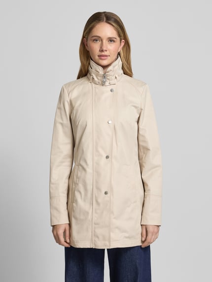 Frauenmodel trägt Trenchcoat mit Stehkragen und Eingrifftaschen von Fuchs Schmitt, beige, Baumwoll-Mix, tailliert, Ganzkörperansicht von vorne.