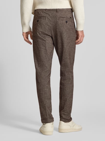 Männermodel trägt Regular Fit Hose mit Gesäßtaschen von JACK & JONES, brauner Stoff mit Bügelfalten, Ganzkörperansicht Rückansicht.