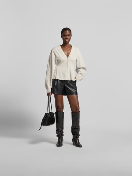 Frauenmodel trägt Cardigan mit Kaschmir-Anteil von ROTATE in Strick-Optik, taillierte Passform, V-Ausschnitt, Kellerfalte, Baumwoll-Mix, Rückansicht Ganzkörperansicht von vorne.