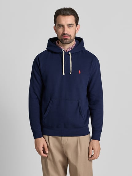 Männermodel trägt Hoodie mit Label-Stitching von Polo Ralph Lauren in Dunkelblau, Baumwoll-Mix, lockerer Schnitt, Ganzkörperansicht von vorne.