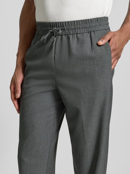 Männermodel trägt Relaxed Fit Hose mit elastischem Bund von Lindbergh in Grau, glatte Textur, mit Tunnelzug, Nahaufnahme Oberkörper.