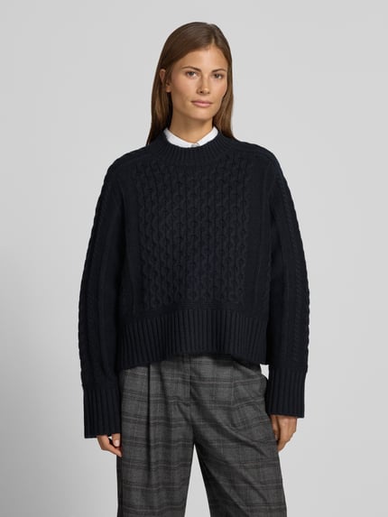 Frauenmodel trägt Strickpullover mit Zopfmuster von Style Icon Collection in Dunkelblau, reine Baumwolle, lockere Passform, Nahaufnahme Oberkörper.