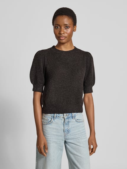 Frauenmodel trägt Regular Fit Pullover mit Puffärmeln von VERO MODA in Dunkelgrau, strukturierte Oberfläche, kombiniert mit heller Jeans, Nahaufnahme Oberkörper.