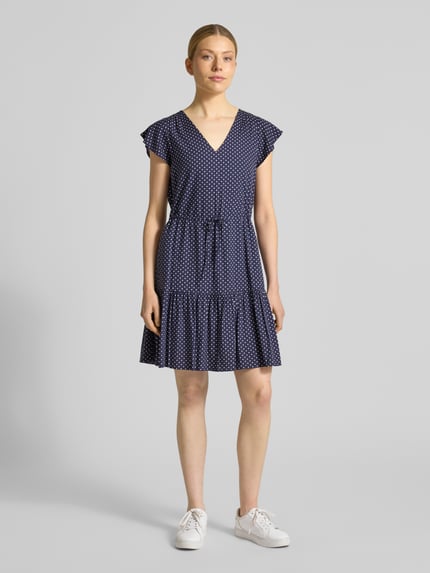 Frauenmodel trägt Minikleid aus reiner Viskose mit V-Ausschnitt von GAP in Dunkelblau mit Muster, tailliert, Tunnelzug, Kurzärmelig, Ganzkörperansicht von vorne.