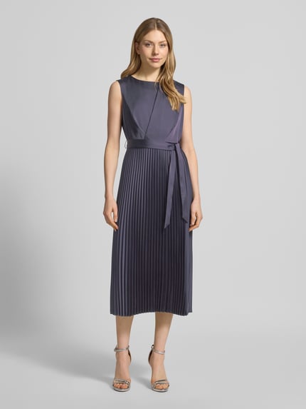 Modelka nosi Midikleid mit Plisseefalten und Bindegürtel von comma, materiał ze stretchu, fason A-linia, plisowana spódnica, pasek, długość tyłu w rozmiarze 36: 35 cm, szerokość w rozmiarze 36: 40 cm, widok całej sylwetki z przodu.