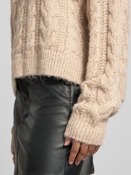 Frauenmodel trägt Oversized Fit Strickpullover mit Zopfmuster von REVIEW in Beige mit Rundhalsausschnitt, Textur grob gestrickt, elastische Abschlüsse, Nahaufnahme Oberkörper, Damen Strickpullover, KI-modifiziertes Bild.