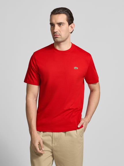 Männermodel trägt Regular Fit Poloshirt aus reiner Baumwolle von Lacoste, effen rood, logo-stiksel, ronde hals, korte mouw, regular fit, pure katoen, vooraanzicht bovenlichaam